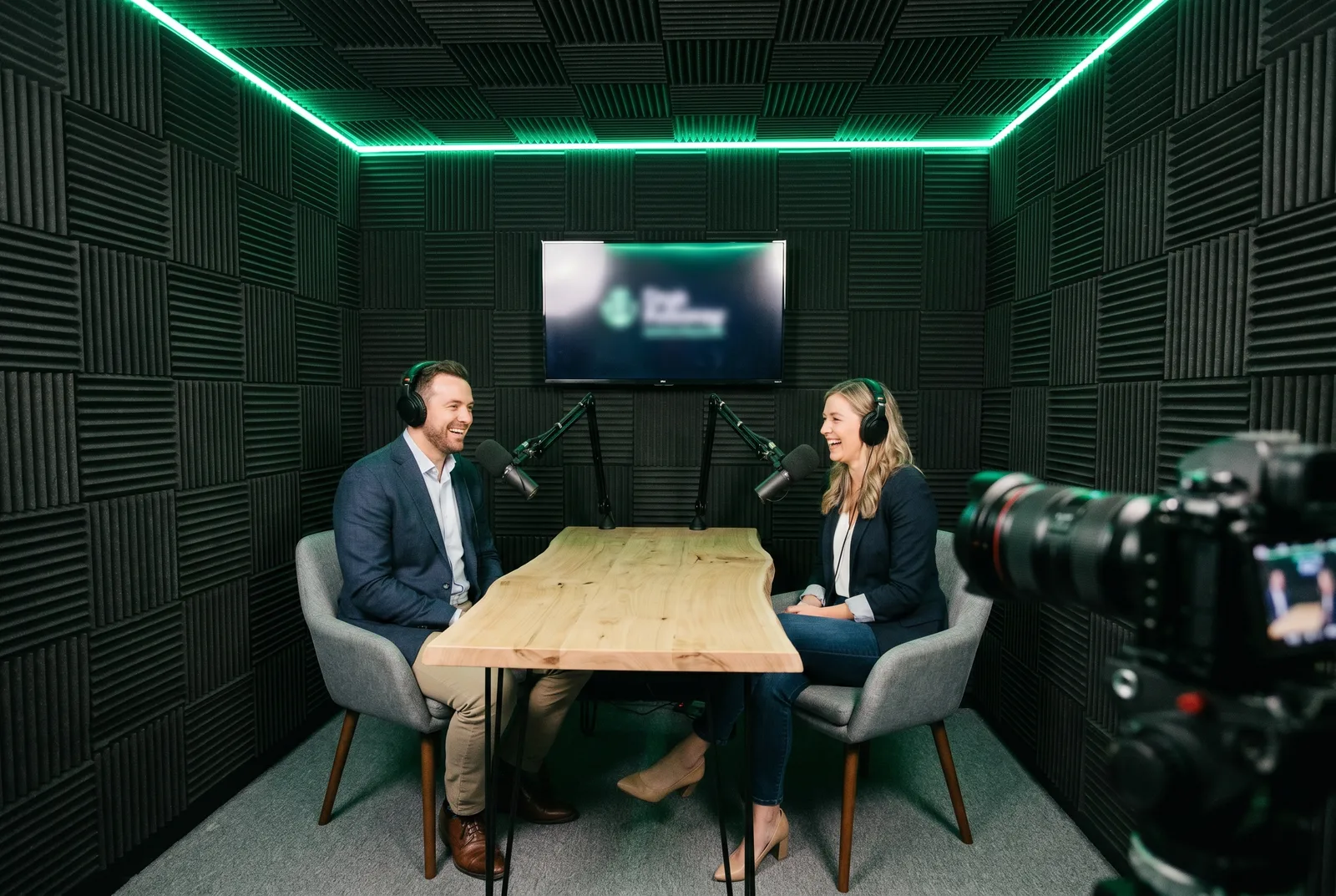 Two people recording a podcast interview across the studio table